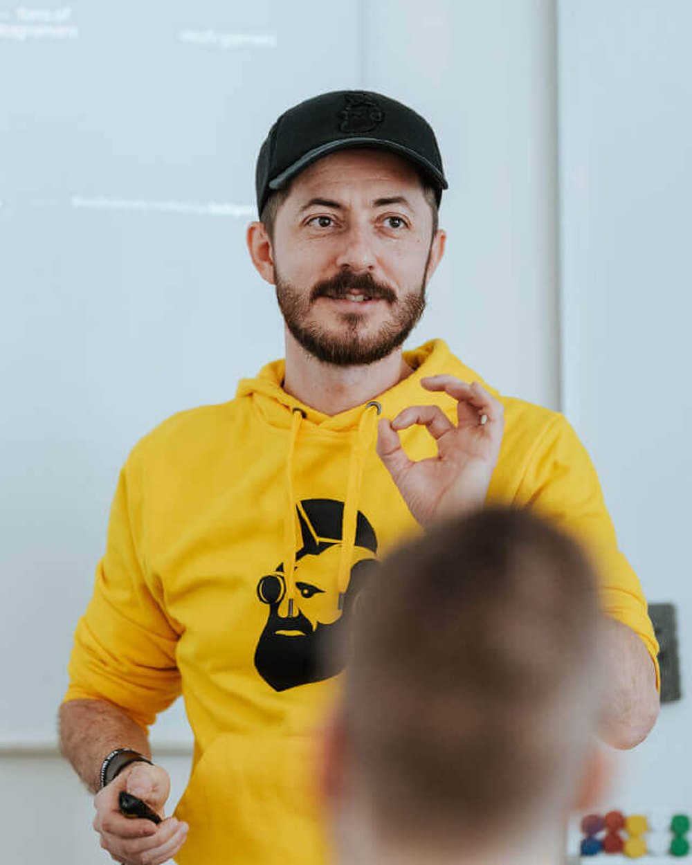 Lektor ve žluté mikině gestikuluje během školení